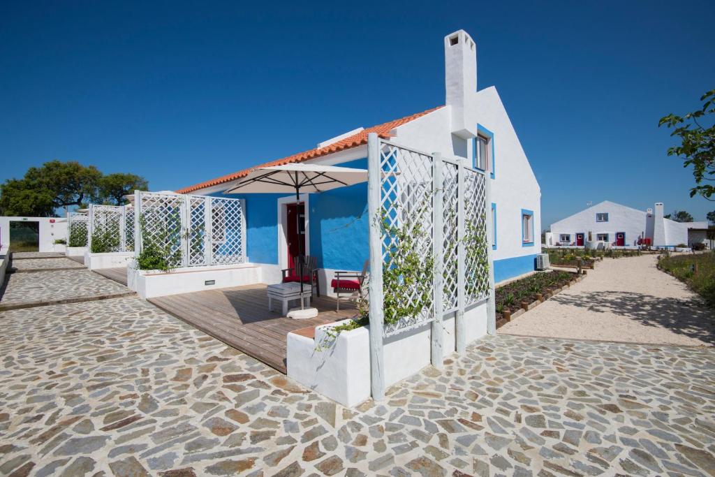 uma casa branca com um guarda-sol numa praia em Monte da Corça Nova em Vila Nova de Milfontes