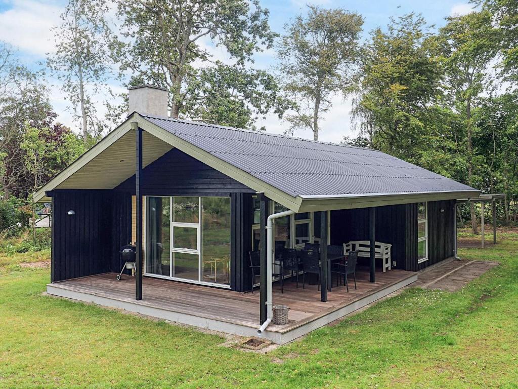 a black shed with a deck with a table at Holiday home for family in Denmark in Løgsted