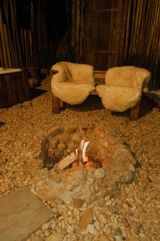 two chairs sitting next to a fire in a room at Espaço Áurea 60km de Curitiba com Cesta de Café da manhã in Campina Grande do Sul