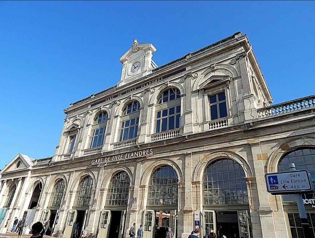 un grand bâtiment avec une tour d'horloge au sommet dans l'établissement SPLENDIDE Appartement pour 4 in front GARE LILLE FLANDRES, à Lille