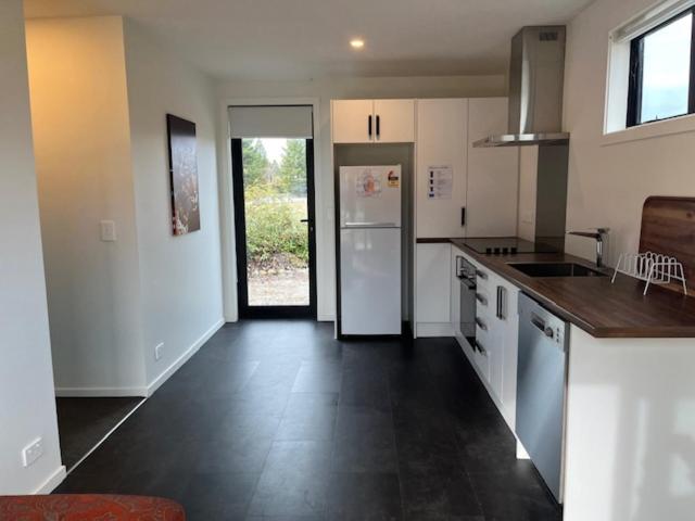 a kitchen with white appliances and a black tile floor at Glen Lyon Road in Twizel