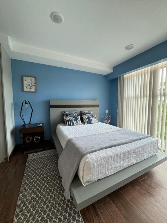 a bedroom with blue walls and a large bed at Lovely Apartment near Costa Rica airport in Heredia
