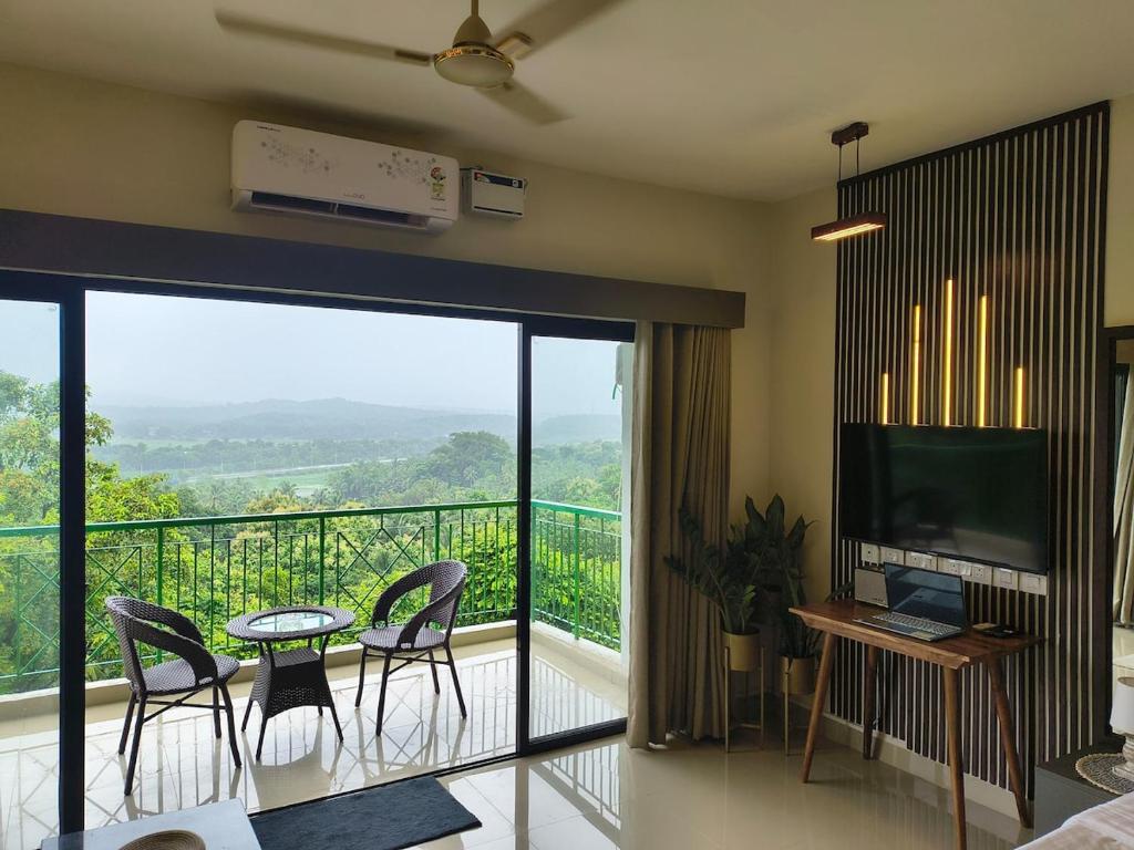 un soggiorno con balcone arredato con tavolo e sedie. di Forest Frame - Kudrat Nilaya Valley View with pool a Canacona