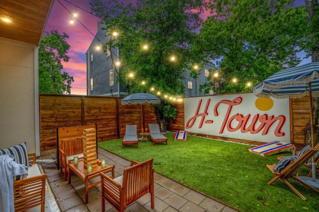 a patio with chairs and umbrellas in a yard at The Bayou Bungalow- 5 mins to downtown, 10 to NRG, Sleeps 12, Amazing backyard! in Houston