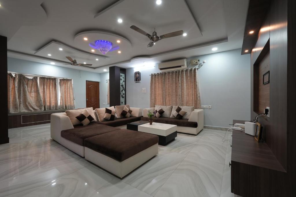 ティルパティにあるPARADISE VILLA A Luxury 5Bhk Home Stayのソファとテーブルのあるリビングルーム
