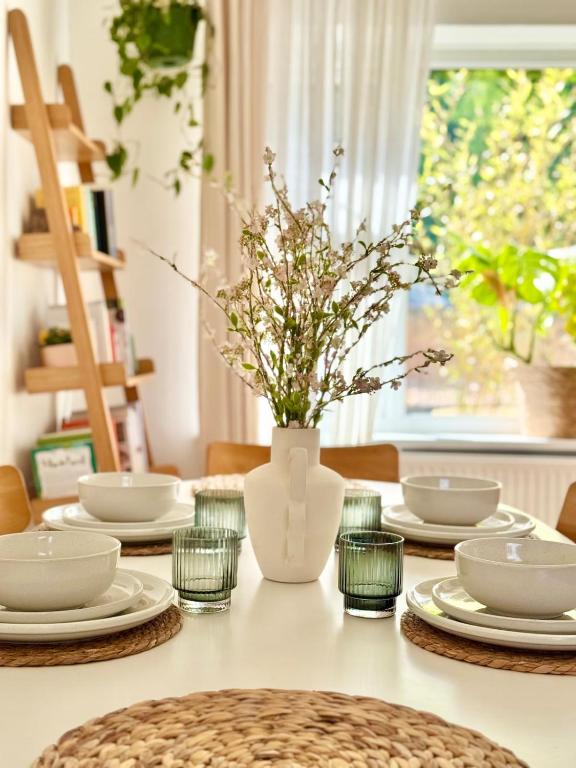a table with plates and a vase with flowers in it at The View on Castle Hill with Lovely Hot Tub in Conwy