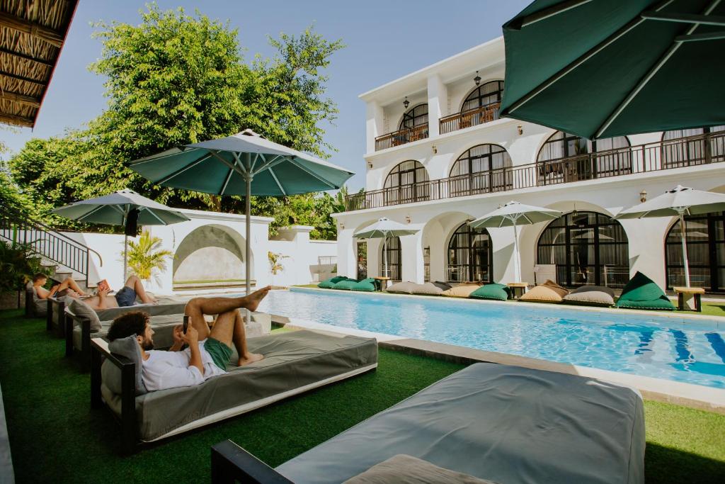 a group of people laying on lounge chairs by a pool at Nuansa Penida Hostel in Nusa Penida
