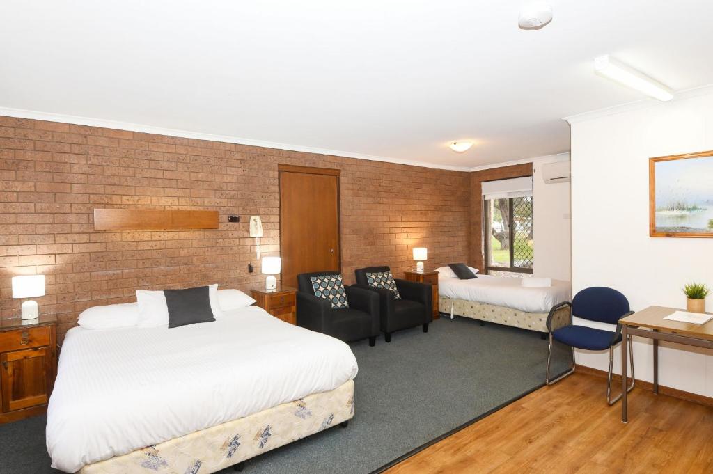 a hotel room with two beds and a desk at Greenacres Motel in Corowa