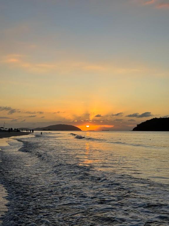 a sunset on a beach with the sun setting at Casa aconchegante à 2 minutos da praia em Prainha de Mambucaba Paraty in Paraty
