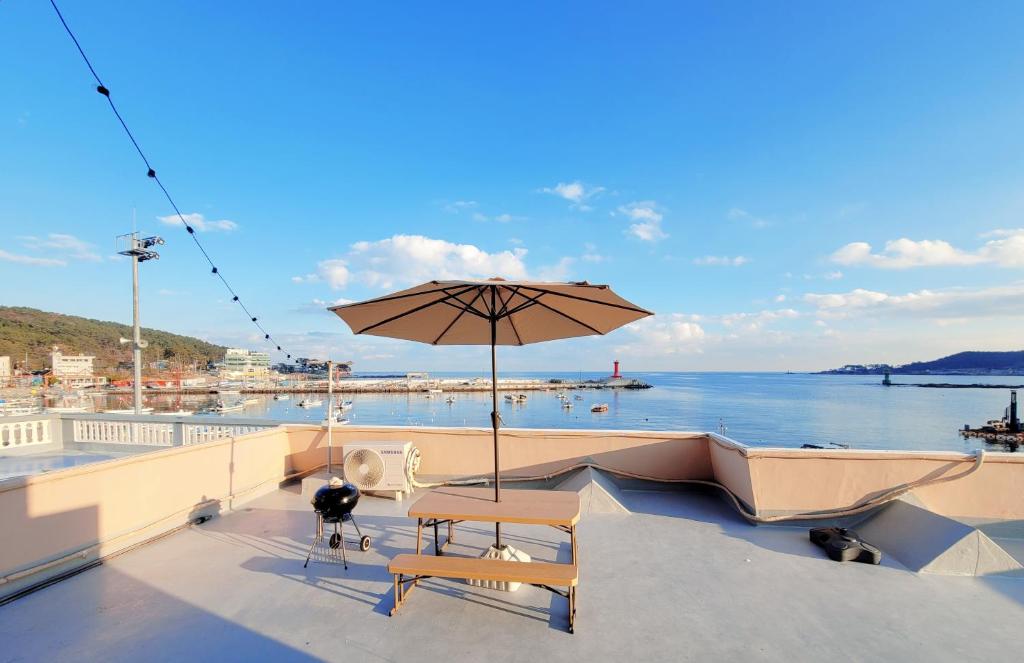 a patio with a table and an umbrella on a boat at Ilgwang 2Floor House in Busan