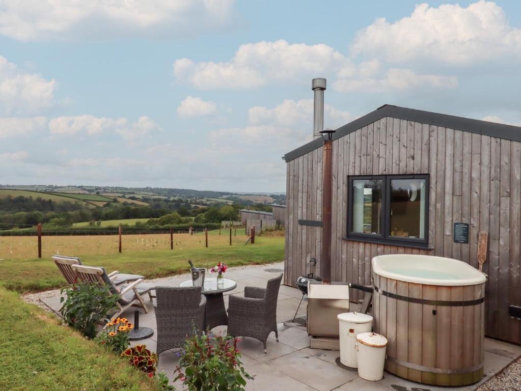 een kleine hut met een hottub en een patio bij The Pennymoor in Tiverton