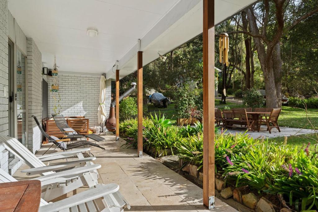 パール・ビーチにあるSalt and Stone Modern Pearl Beach Stay 2 Mins to Oceanの白い椅子とテーブルとベンチのあるパティオ