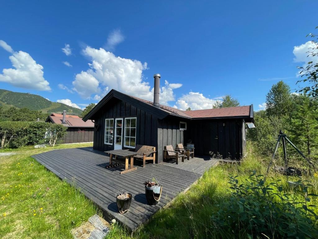 una cabina nera con ponte in legno in un cortile di Revehiet - 3 bedroom cabin in the center of Geilo a Geilo