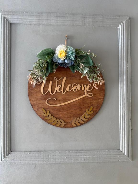 a wooden sign with the word welcome on a wall at Chai Homestay in Butuan