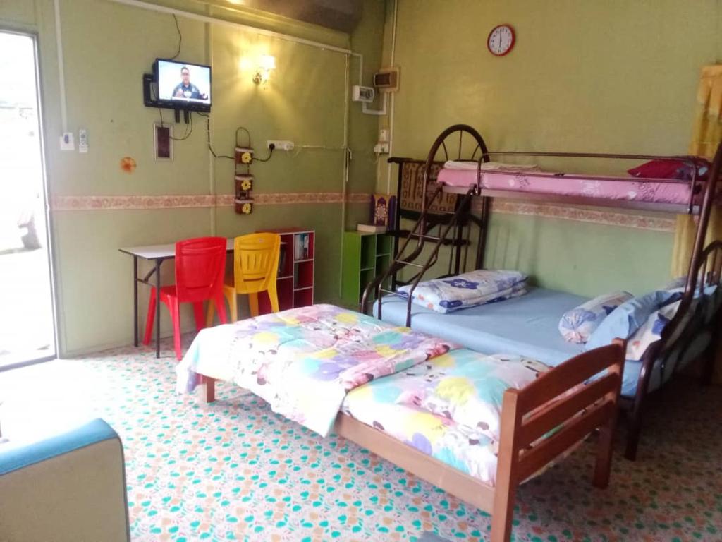 two beds in a room with a table and chairs at Roomstay Nina Marang Pulau Kapas in Marang