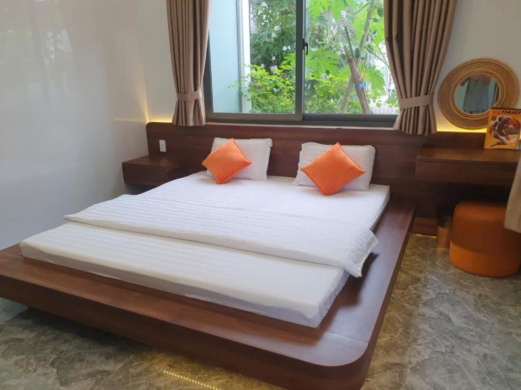 a bedroom with a bed with orange pillows and a window at Happy House Gành Dầu in Phu Quoc