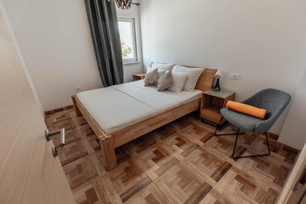 Un pequeño dormitorio con una cama y una silla. en Elia apartments, en Ražanj
