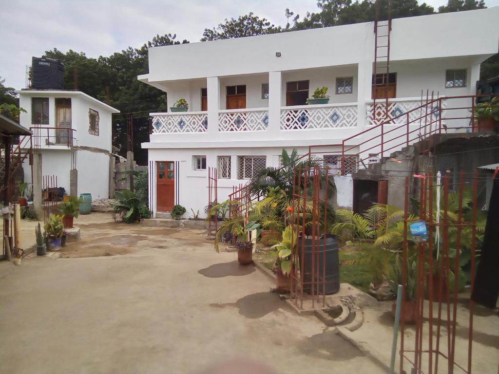 a white house with a lot of plants in front of it at MUNDO GUEST & STUDIO APARTMENTS, MTWAPA,mombasa in Mtwapa