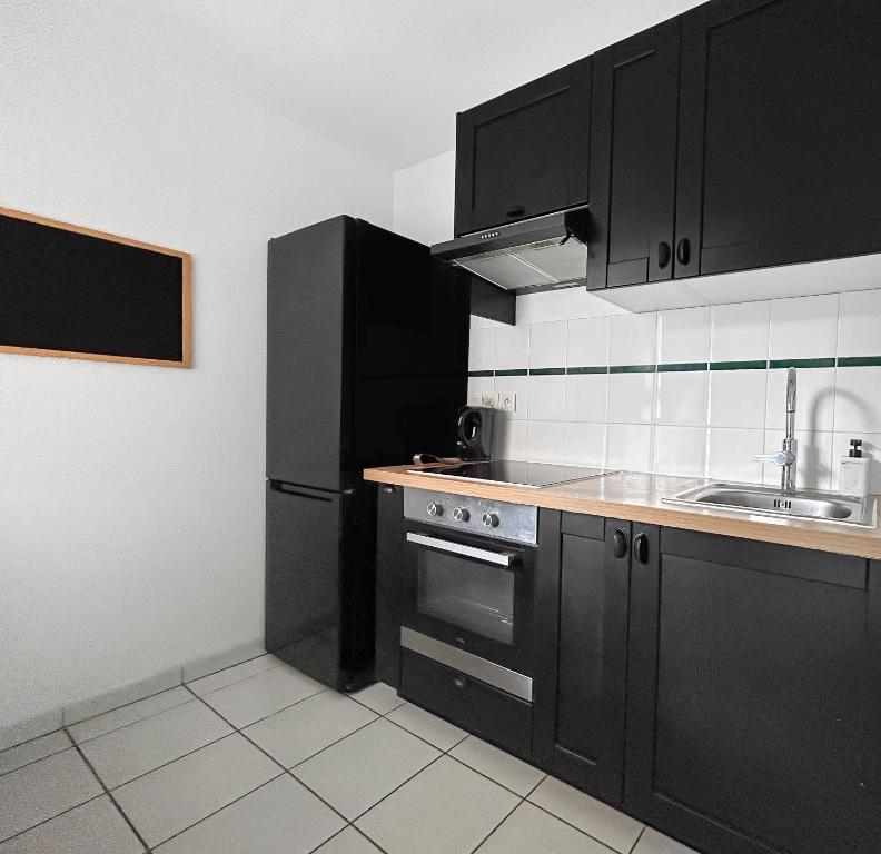 a kitchen with black cabinets and a sink at T2 Lumineux avec balcon - proche Airbus - Toulouse in Plaisance-du-Touch