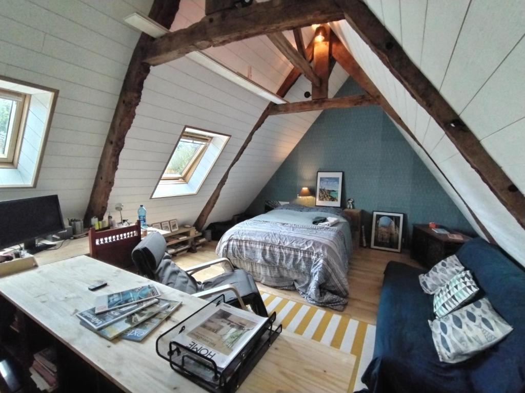 - une chambre mansardée avec un lit et une table dans l'établissement La parenthèse verte, à Meillac