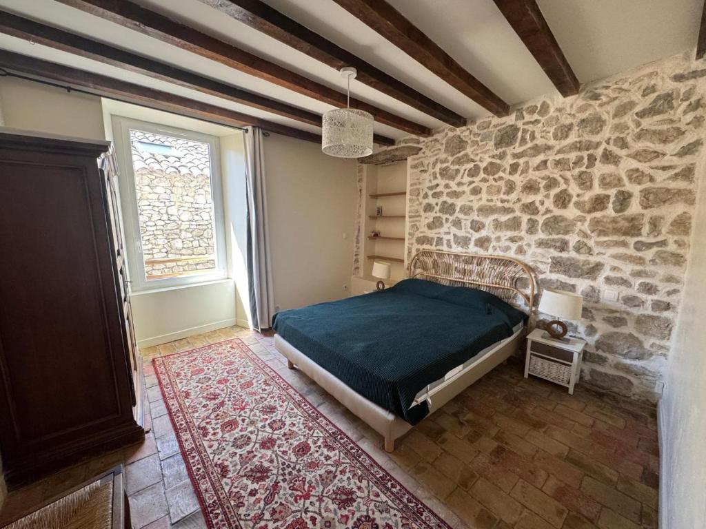 une chambre avec un lit et un mur en pierre dans l'établissement Maison de Charme près de Lussan & Uzès Calme et Authentique, à Vallérargues