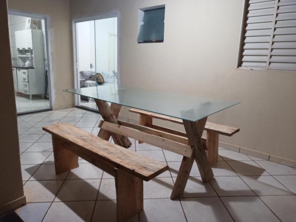 un tavolo in vetro e una panca in una stanza di Iporã casa simples Ar-cond, wi-fi, smartv, máquina de lavar 6 pessoas, equipado com churrasqueira, garagem para 4 carros sendo 2 coberta, Hop Independente ad Araçatuba