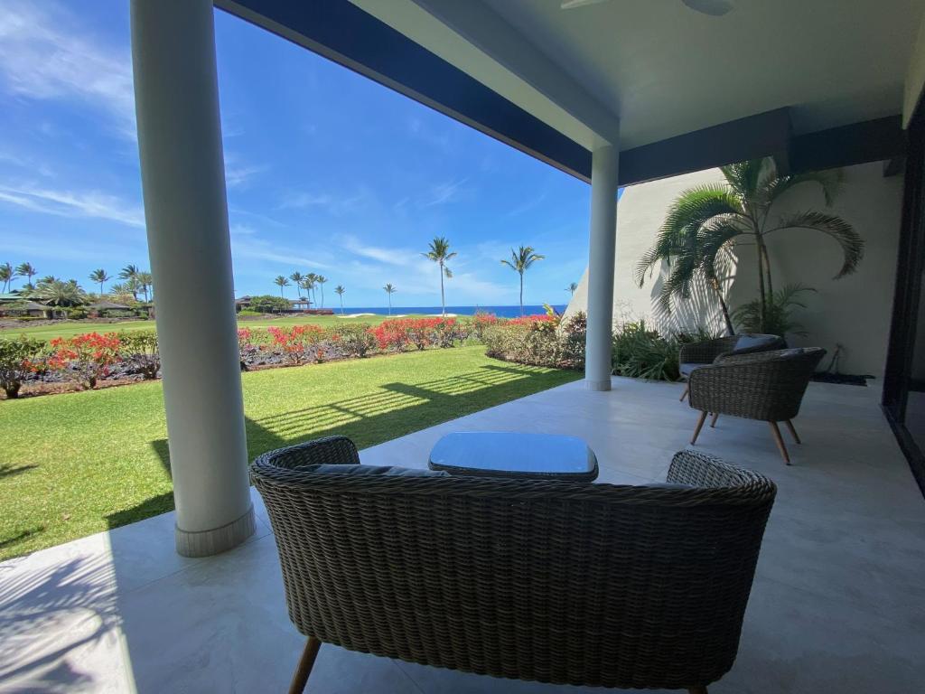 a porch with wicker chairs and a view of the ocean at Mauna Lani Point Newly Furnished ocean golf views in Waikoloa