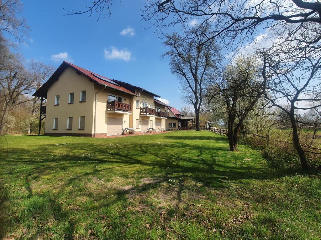 a large house on a grassy field with trees at Gasthaus Bukoitza in Radensdorf