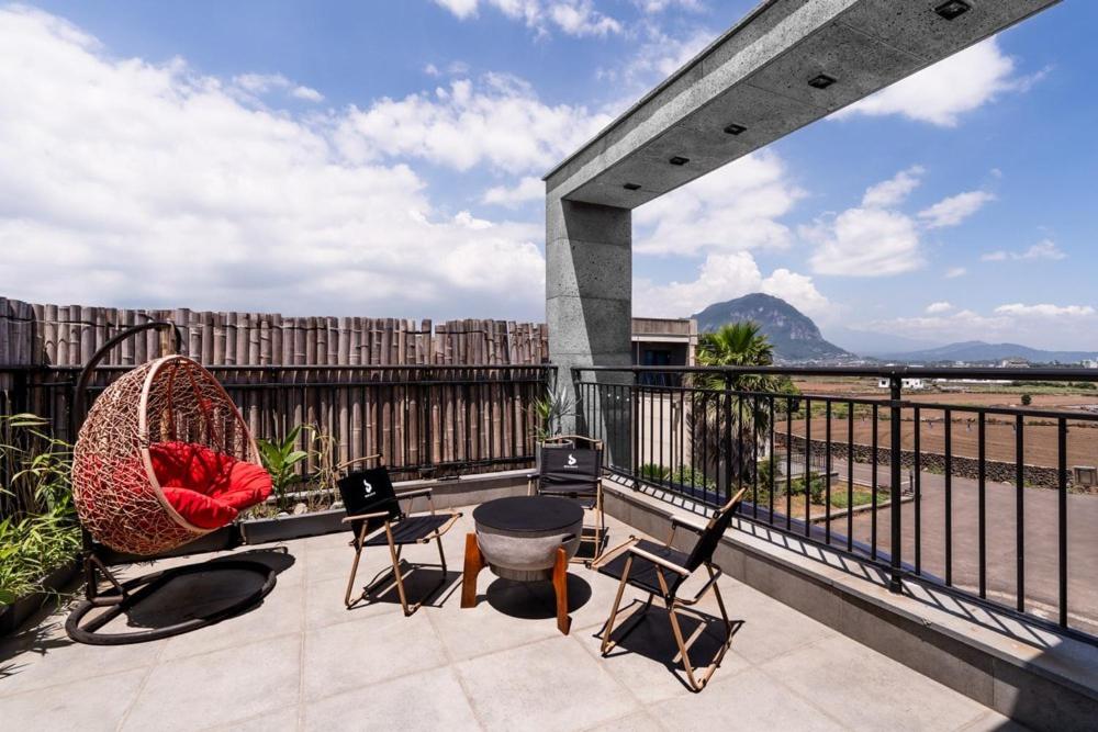 un patio avec des chaises et un barbecue sur un balcon dans l'établissement Jeju Jebistay, à Sagye-ri