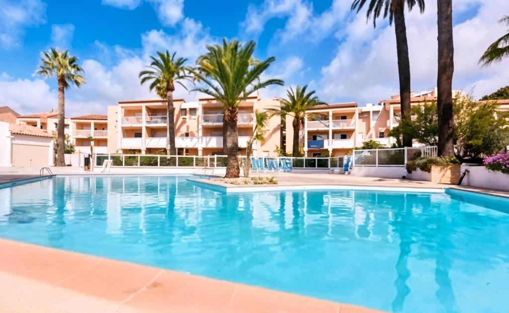 une grande piscine avec des palmiers en face d'un bâtiment dans l'établissement FRGK 