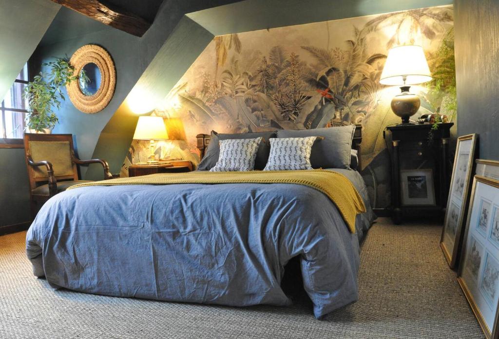 a bedroom with a king sized bed with a floral wallpaper at Cottage du collectionneur in Saint-Laurent-du-Mottay