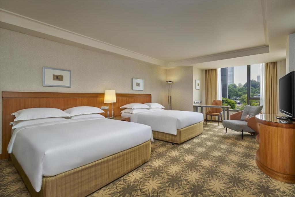 A two-bed room with a large window overlooking trees and high-rises.