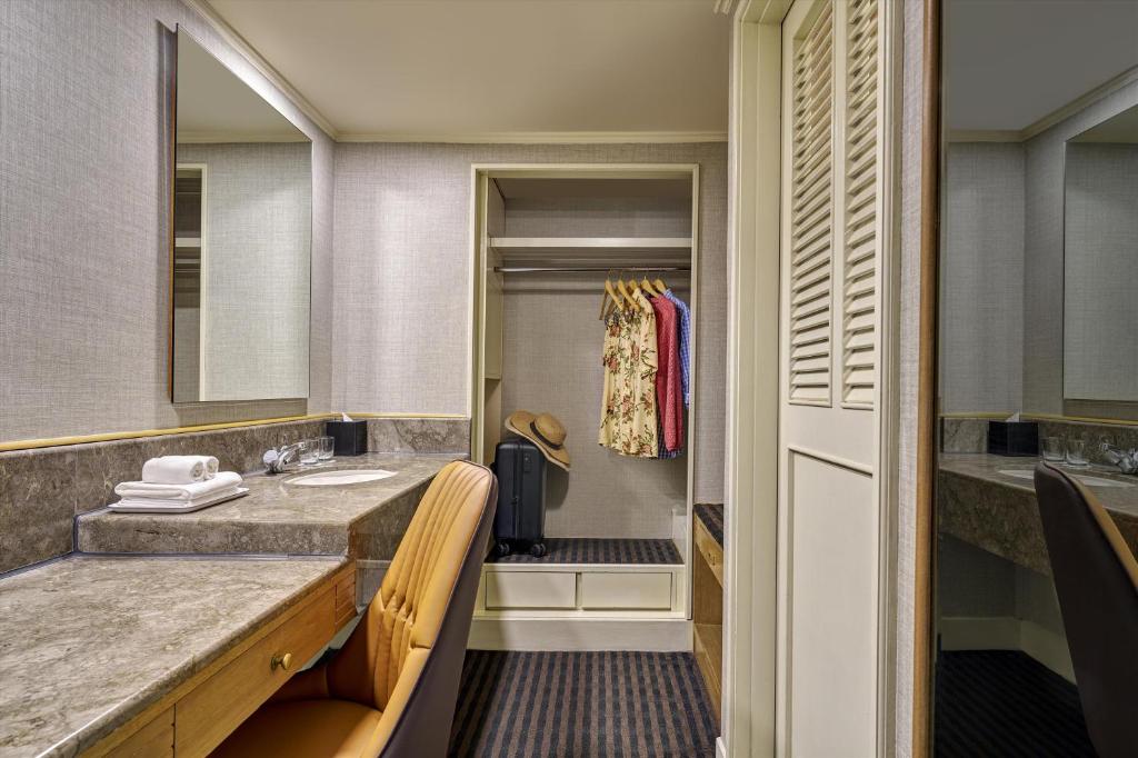 A hotel-room vanity and open wardrobe with a suitcase niche.