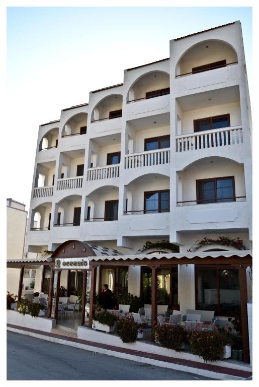 a white building with tables and chairs in front of it at Oceanis Hotel in Karpathos