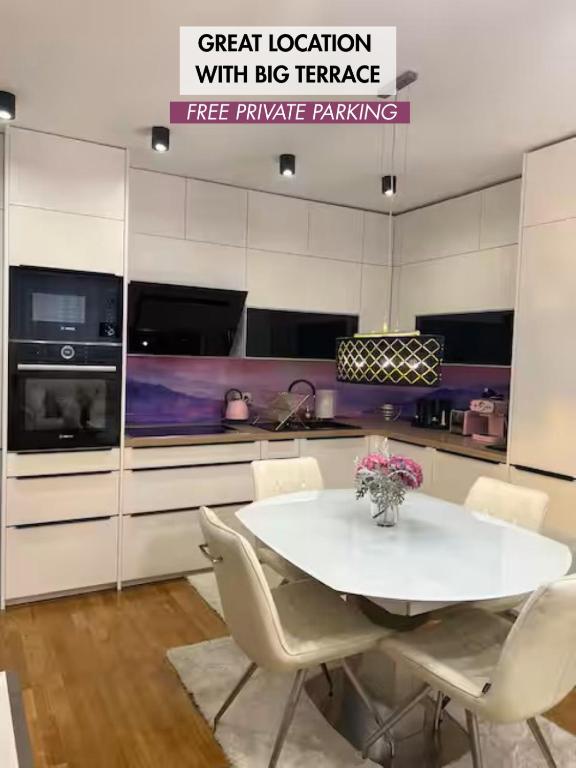 a white kitchen with a white table and chairs at Apartment Anaa in Radovljica