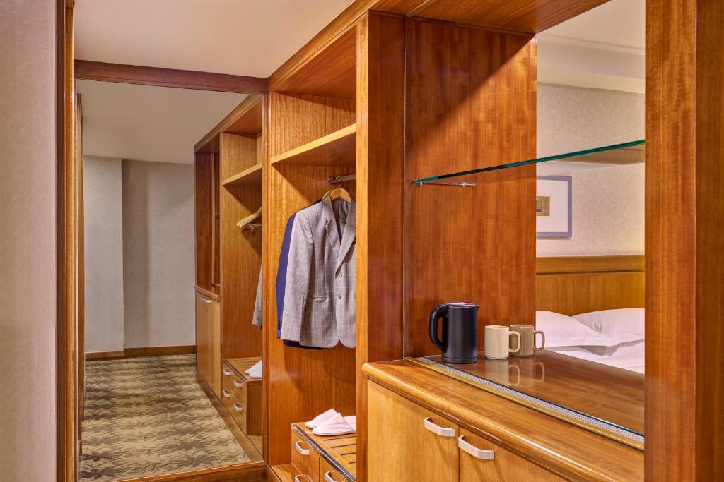 A wood-lined wardrobe and refreshment area with hanging space, drawers and a kettle.