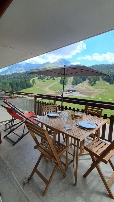 a wooden table with chairs and an umbrella on a balcony at Studio Superdevoluy 4 personnes au pied des pistes in Superdevoluy