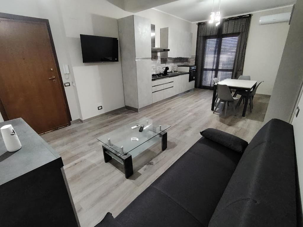 a living room with a black couch and a kitchen at New House in Lamezia Terme