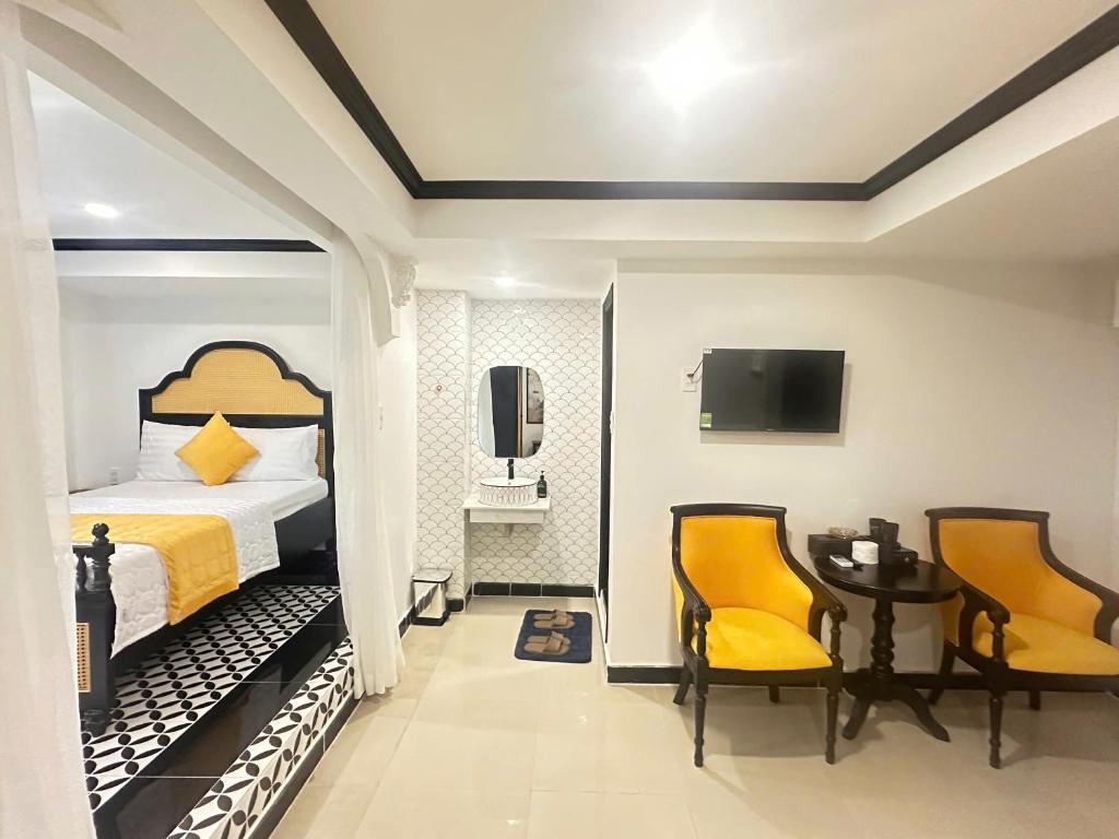 a bedroom with a bed and two chairs and a table at Phú Gia Luxury in Ho Chi Minh City
