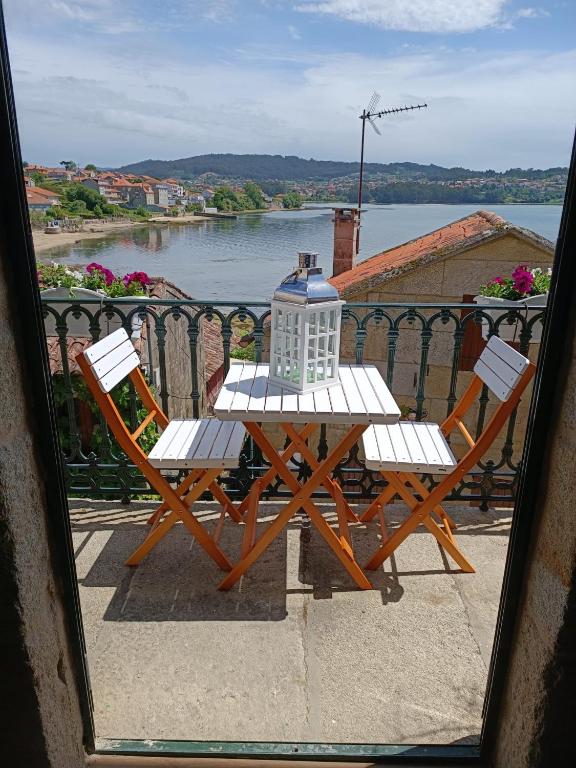 a table and chairs on a balcony with a view of the water at Noelmar II Combarro in Combarro