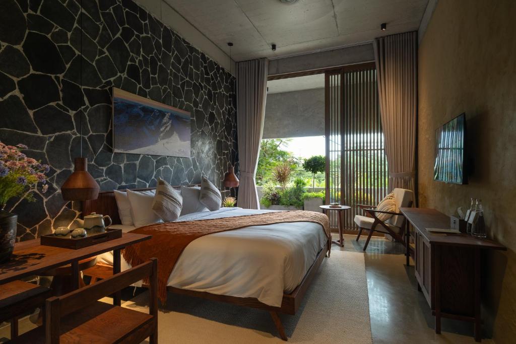 a bedroom with a large bed and a stone wall at Wazen Retreat Villa Danang in Da Nang