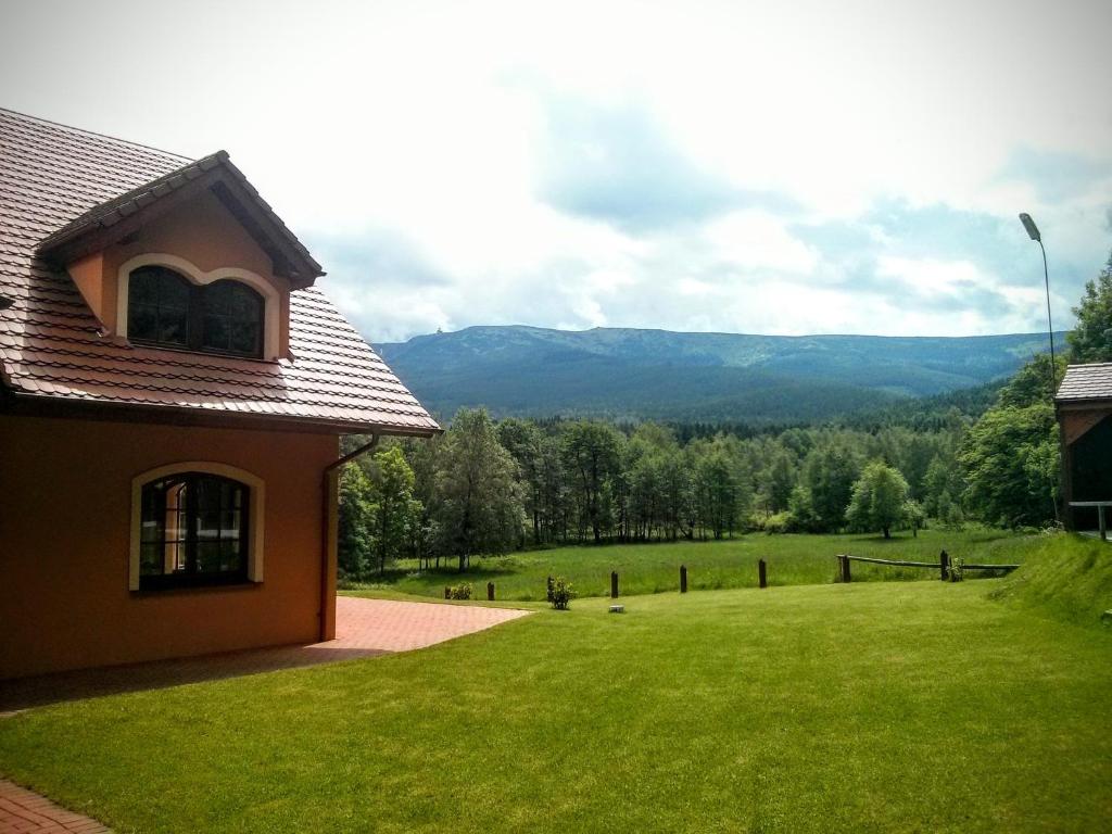a house with a green yard with mountains in the background at Willa Leśna Polana in Szklarska Poręba