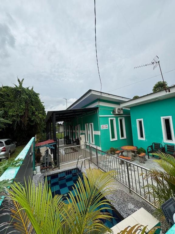 a green house with a swimming pool in front of it at Siti Roomstay Langkawi in Gua Sai