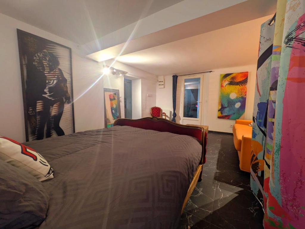 een slaapkamer met een bed en schilderijen aan de muur bij Pigments & Paillettes in Draguignan