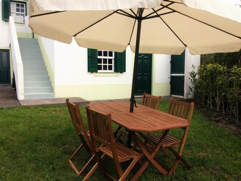 una mesa de madera y sillas bajo una sombrilla en House Andrade, en Praia do Norte