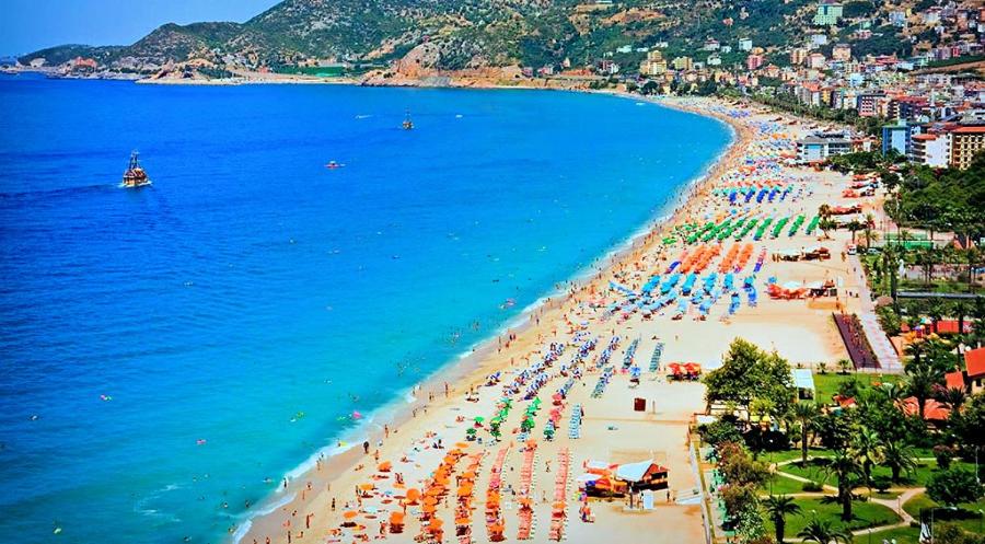 an aerial view of a beach with umbrellas and people at Dreamy luxury two-bedroom penthouse apartment with special forest, mountain and sea views in Alanya