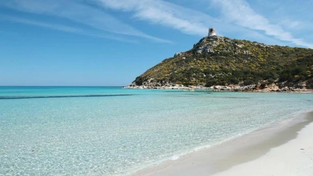 a beach with a lighthouse on top of a hill at Sole e Luna in San Vito