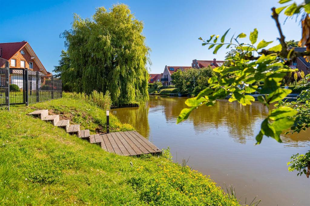 a river with a wooden path next to a house at Grachtenblick I in Greetsiel