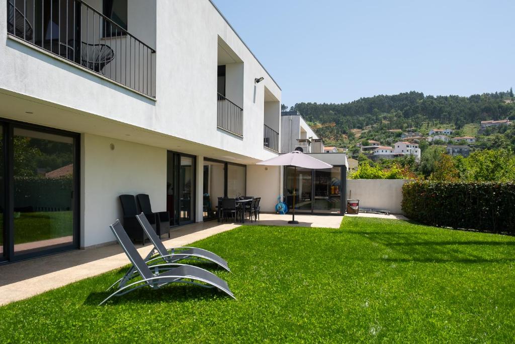 a yard with two chairs in the grass next to a building at Casa Horizontes de Arouca in Arouca