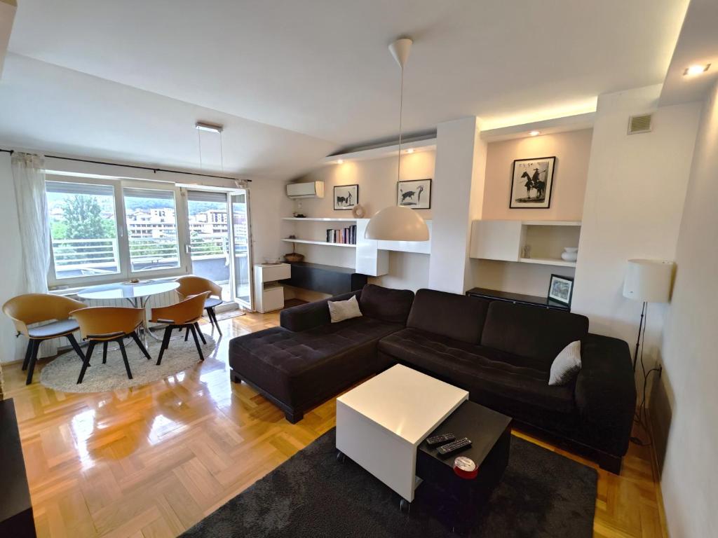Una sala de estar con un sofá negro y una mesa. en Sunny River BL, en Banja Luka